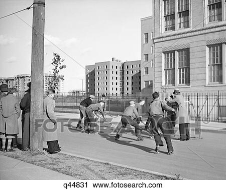 Stock Image - 1930s GROUP TEEN BOYS PLAYING STREET HOCKEY IN BOROUGH OF QUEENS NEW YORK CITY USA. Fotosearch