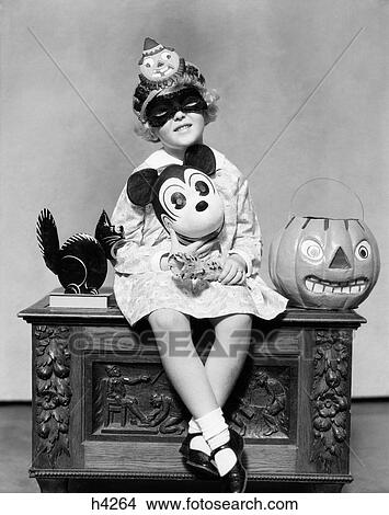 1930S Little Girl Holding Mickey Mouse Toy Wearing Mask Clown Hat Looking At Camera Sitting Beside Black Cat Halloween Pumpkin View Large Photo Image Picture - 1930S Little Girl Holding Mickey Mouse Toy Wearing Mask Clown Hat Looking At Camera Sitting Beside Black Cat Halloween Pumpkin . Fotosearch
