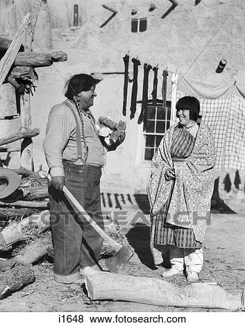 1930s NATIVE AMERICAN COUPLE WOMAN IN TYPICAL COSTUME MAN IN JEANS CHOPPING FIREWOOD WITH AX SAN ILDEFONSO PUEBLO NEW MEXICO USA View Large Photo Image Stock Photo - 1930s NATIVE AMERICAN COUPLE WOMAN IN TYPICAL COSTUME MAN IN JEANS CHOPPING FIREWOOD WITH AX SAN ILDEFONSO PUEBLO NEW MEXICO USA. Fotosearch