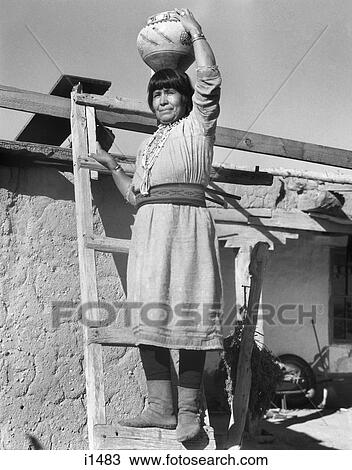 1930s NATIVE AMERICAN INDIAN WOMAN ON LADDER HOLDING OLLA POTTERY JAR ON HER HEAD COCHITI PUEBLO NEW MEXICO USA View Large Photo Image Stock Image - 1930s NATIVE AMERICAN INDIAN WOMAN ON LADDER HOLDING OLLA POTTERY JAR ON HER HEAD COCHITI PUEBLO NEW MEXICO USA. Fotosearch