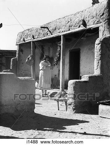 1930s NATIVE AMERICAN INDIAN WOMAN HANGING CHILI PEPPERS TO DRY COCHITI PUEBLO NEW MEXICO USA View Large Photo Image Stock Photo - 1930s NATIVE AMERICAN INDIAN WOMAN HANGING CHILI PEPPERS TO DRY COCHITI PUEBLO NEW MEXICO USA. Fotosearch