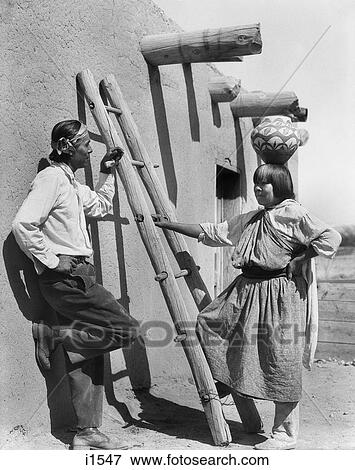 1930s NATIVE AMERICAN MAN AND WOMAN BY ADOBE BUILDING POTTERY OLLA WATER JUG ON HER HEAD SAN ILDEFONSO PUEBLO NEW MEXICO USA View Large Photo Image Stock Photo - 1930s NATIVE AMERICAN MAN AND WOMAN BY ADOBE BUILDING POTTERY OLLA WATER JUG ON HER HEAD SAN ILDEFONSO PUEBLO NEW MEXICO USA. Fotosearch