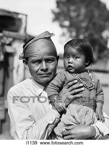 1930s NATIVE AMERICAN NAVAJO MAN FATHER HOLDING BABY GIRL DAUGHTER LOOKING AT CAMERA View Large Photo Image Stock Photo - 1930s NATIVE AMERICAN NAVAJO MAN FATHER HOLDING BABY GIRL DAUGHTER LOOKING AT CAMERA. Fotosearch