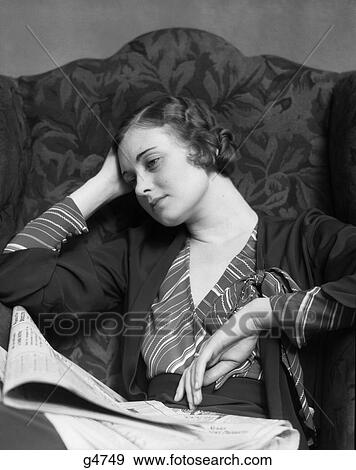 1930s SAD WOMAN SITTING IN HIGH BACK ARMCHAIR WEARING STRIPED BLOUSE LEANING HEAD ON HAND NEWSPAPER IN LAP View Large Photo Image Stock Photo - 1930s SAD WOMAN SITTING IN HIGH BACK ARMCHAIR WEARING STRIPED BLOUSE LEANING HEAD ON HAND NEWSPAPER IN LAP. Fotosearch