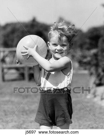1930s SMILING BOY SUMMER OUTDOOR PLAYING IN BACKYARD LOOKING AT CAMERA READY TO TOSS BALL View Large Photo Image Stock Photo - 1930s SMILING BOY SUMMER OUTDOOR PLAYING IN BACKYARD LOOKING AT CAMERA READY TO TOSS BALL. Fotosearch