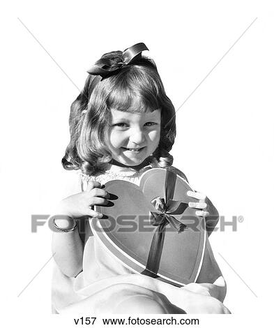 1930s SMILING GIRL JUVENILE HOLDING HEART SHAPED CANDY BOX LOOKING AT CAMERA View Large Photo Image Stock Photo - 1930s SMILING GIRL JUVENILE HOLDING HEART SHAPED CANDY BOX LOOKING AT CAMERA. Fotosearch