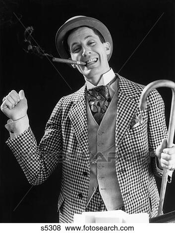 1930S Smiling Man Carnival Barker Con Man In Checkered Suit With Cane In Hand & Cigar In Mouth Looking At Camera View Large Photo Image Stock Photo - 1930S Smiling Man Carnival Barker Con Man In Checkered Suit With Cane In Hand & Cigar In Mouth Looking At Camera. Fotosearch