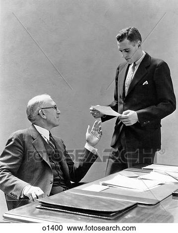 1930s TWO MEN AT DESK IN OFFICE LOOKING AT PAPER View Large Photo Image Stock Image - 1930s TWO MEN AT DESK IN OFFICE LOOKING AT PAPER. Fotosearch