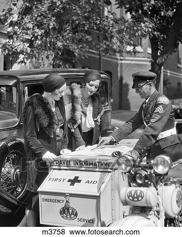 Stock Photo - 1930s TWO WOMEN MOTORISTS TALKING TO AAA MOBILE SERVICE OFFICER RIDING ROAD SERVICE AND FIRST AID EMERGENCY SIDECAR MOTORCYCLE. Fotosearch