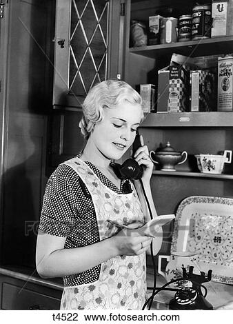 1930s WOMAN HOMEMAKER IN APRON STANDING IN KITCHEN TALKING ON TELEPHONE View Large Photo Image Stock Image - 1930s WOMAN HOMEMAKER IN APRON STANDING IN KITCHEN TALKING ON TELEPHONE. Fotosearch