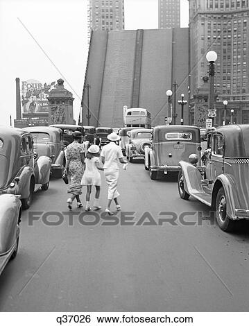 1937 TWO ANONYMOUS STYLISH WOMEN AND YOUNG GIRL CROSSING MICHIGAN AVENUE BRIDGE AMID TRAFFIC DOWNTOWN CHICAGO IL USA View Large Photo Image Stock Photograph - 1937 TWO ANONYMOUS STYLISH WOMEN AND YOUNG GIRL CROSSING MICHIGAN AVENUE BRIDGE AMID TRAFFIC DOWNTOWN CHICAGO IL USA. Fotosearch