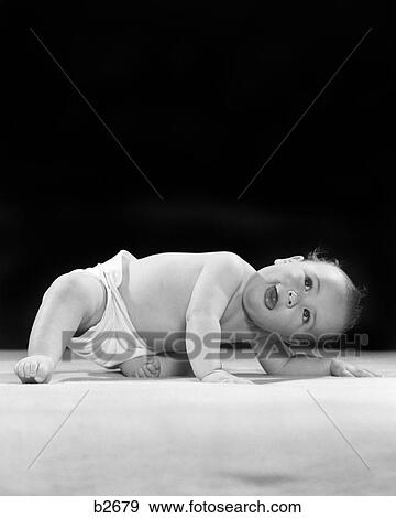 Stock Photo - 1940s 1950s DIAPERED BABY BENDING DOWN LOOKING UP. Fotosearch