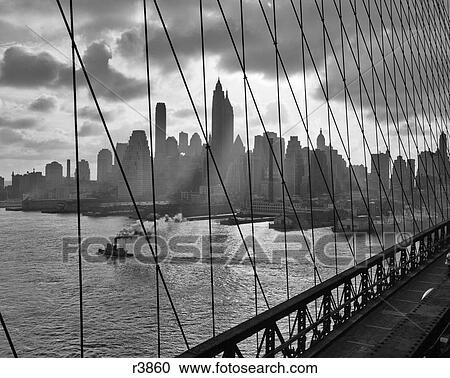 1940S 1950S Downtown Skyline Manhattan Seen Through Cables Of Brooklyn Bridge Tug Boat In East River Nyc Ny Usa View Large Photo Image Stock Image - 1940S 1950S Downtown Skyline Manhattan Seen Through Cables Of Brooklyn Bridge Tug Boat In East River Nyc Ny Usa. Fotosearch