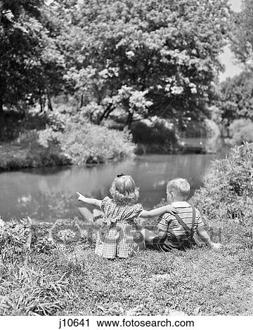 1940s 1950s GIRL BOY SITTING IN GRASS BESIDE POND STREAM SISTER POINTING ARM ON BROTHERS SHOULDER SUMMERTIME View Large Photo Image Stock Image - 1940s 1950s GIRL BOY SITTING IN GRASS BESIDE POND STREAM SISTER POINTING ARM ON BROTHERS SHOULDER SUMMERTIME. Fotosearch