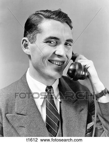 1940s 1950s MAN IN SUIT TALKING ON TELEPHONE SMILING LOOKING AT CAMERA View Large Photo Image Stock Image - 1940s 1950s MAN IN SUIT TALKING ON TELEPHONE SMILING LOOKING AT CAMERA. Fotosearch