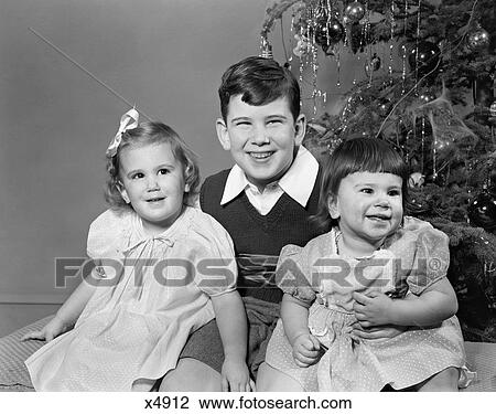 1940s 1950s SMILING BIG BROTHER AND TWO SISTERS SITTING TOGETHER BY CHRISTMAS TREE View Large Photo Image Stock Image - 1940s 1950s SMILING BIG BROTHER AND TWO SISTERS SITTING TOGETHER BY CHRISTMAS TREE. Fotosearch