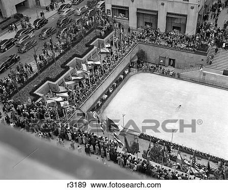 Stock Photo - 1940S Crowd Watching Skater Rockefeller Center Ice Skating Rink Midtown Manhattan New York City. Fotosearch