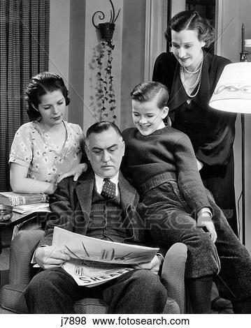 Stock Photo - 1940s FAMILY OF FOUR WOMAN MOTHER TEENAGE DAUGHTER GIRL AND SON BOY SITTING AROUND FATHER MAN READING NEWSPAPER. Fotosearch
