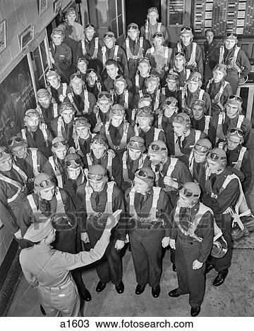 Stock Image - 1940s NEW AVIATION OFFICERS GET LAST MINUTE PARACHUTE INSTRUCTION BEFORE TRAINING FLIGHT. Fotosearch