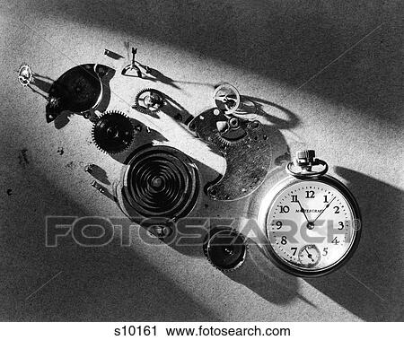 Stock Image - 1940s POCKET WATCH AND PARTS SPRINGS GEARS MECHANISM IN DRAMATIC LIGHT. Fotosearch