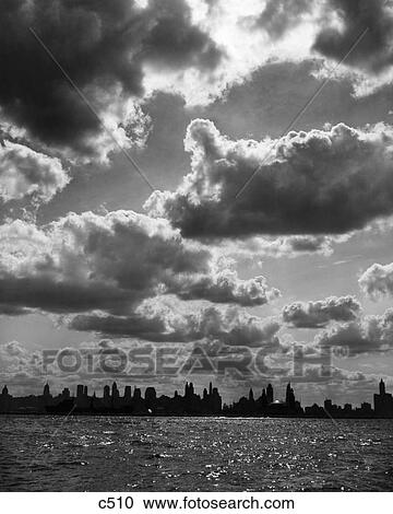 Stock Image - 1940s SILHOUETTED SKYLINE OF CHICAGO UNDER SKY FULL OF CLOUDS. Fotosearch