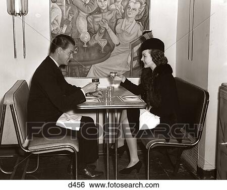 1940s SMILING YOUNG COUPLE MAN WOMAN SITTING TOGETHER ON CHROME ART DECO STYLE TABLE AND CHAIR FURNITURE IN MODERN CAFE View Large Photo Image Stock Photograph - 1940s SMILING YOUNG COUPLE MAN WOMAN SITTING TOGETHER ON CHROME ART DECO STYLE TABLE AND CHAIR FURNITURE IN MODERN CAFE. Fotosearch