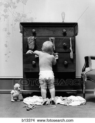 1940S Toddler Baby Pulling Clothes Out Of Bureau Drawers Making A Mess View Large Photo Image Picture - 1940S Toddler Baby Pulling Clothes Out Of Bureau Drawers Making A Mess. Fotosearch