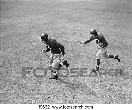 1940s TWO MEN PLAYING FOOTBALL WEARING LEATHER HELMETS ONE RUNNING WITH FOOTBALL OTHER BLOCKING FOR HIM View Large Photo Image Stock Image - 1940s TWO MEN PLAYING FOOTBALL WEARING LEATHER HELMETS ONE RUNNING WITH FOOTBALL OTHER BLOCKING FOR HIM. Fotosearch