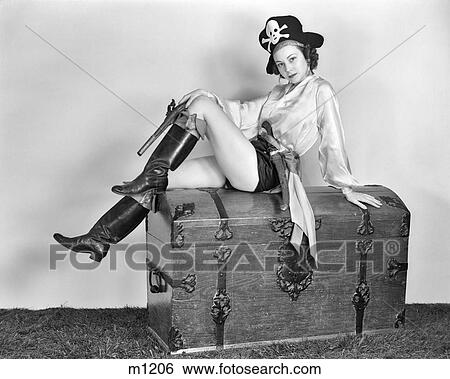 1940s WOMAN WEARING PIRATE COSTUME SITTING ON TREASURE TRUNK HOLDING FLINTLOCK PISTOL LOOKING AT CAMERA View Large Photo Image Stock Photograph - 1940s WOMAN WEARING PIRATE COSTUME SITTING ON TREASURE TRUNK HOLDING FLINTLOCK PISTOL LOOKING AT CAMERA. Fotosearch