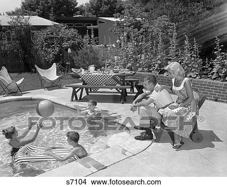 1950S 1960S Backyard Patio Pool Parents Mother Father Man Woman Seated Watching Three Children Playing In Water View Large Photo Image Picture - 1950S 1960S Backyard Patio Pool Parents Mother Father Man Woman Seated Watching Three Children Playing In Water. Fotosearch