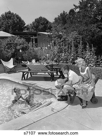 1950S 1960S Backyard Patio Pool Parents Mother Father Man Woman Seated Watching Three Children Playing In Water View Large Photo Image Stock Photo - 1950S 1960S Backyard Patio Pool Parents Mother Father Man Woman Seated Watching Three Children Playing In Water . Fotosearch