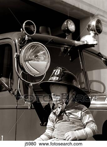 1950s 1960s BOY WEARING FIREMAN SAFETY HELMET IN FRONT OF FIRE TRUCK View Large Photo Image Stock Image - 1950s 1960s BOY WEARING FIREMAN SAFETY HELMET IN FRONT OF FIRE TRUCK. Fotosearch