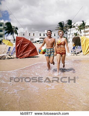1950s 1960s HAPPY COUPLE LOOKING AT CAMERA RUNNING ON TROPICAL BEACH FLORIDA USA View Large Photo Image Stock Photo - 1950s 1960s HAPPY COUPLE LOOKING AT CAMERA RUNNING ON TROPICAL BEACH FLORIDA USA. Fotosearch