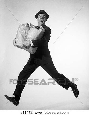 1950s 1960s HAPPY EXCITED MAN WEARING BUSINESS SUIT HAT CARRYING GROCERY SHOPPING BAGS RUNNING JUMPING IN AIR LOOKING AT CAMERA View Large Photo Image Stock Image - 1950s 1960s HAPPY EXCITED MAN WEARING BUSINESS SUIT HAT CARRYING GROCERY SHOPPING BAGS RUNNING JUMPING IN AIR LOOKING AT CAMERA. Fotosearch
