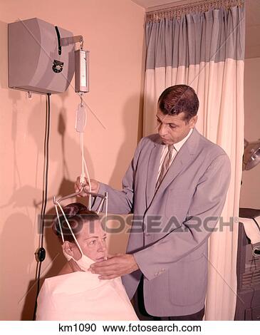 1950s 1960s MAN TECHNICIAN ADJUSTING TENSION ON WOMAN PATIENT CHIN BRACE NECK TRACTION MEDICAL EQUIPMENT View Large Photo Image Stock Image - 1950s 1960s MAN TECHNICIAN ADJUSTING TENSION ON WOMAN PATIENT CHIN BRACE NECK TRACTION MEDICAL EQUIPMENT. Fotosearch