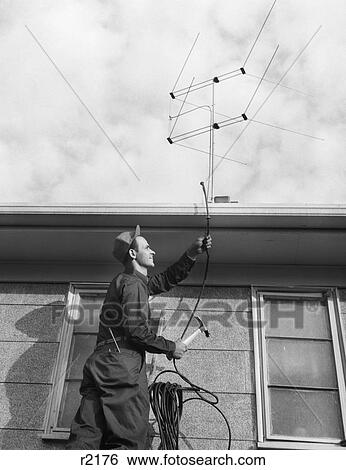 1950S 1960S Man Worker On Ladder Running Television Cable To Antenna On Roof Of House View Large Photo Image Stock Photograph - 1950S 1960S Man Worker On Ladder Running Television Cable To Antenna On Roof Of House. Fotosearch
