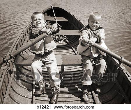 1950s 1960s PAIR OF BOYS SITTING IN BOAT EACH HOLDING ONE OAR STRUGGLING TO ROW View Large Photo Image Stock Image - 1950s 1960s PAIR OF BOYS SITTING IN BOAT EACH HOLDING ONE OAR STRUGGLING TO ROW. Fotosearch