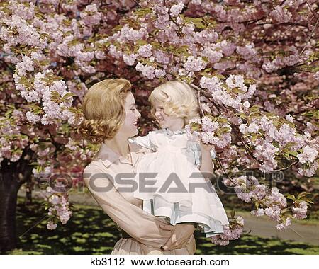 1950s 1960s REDHEAD MOTHER HOLDING BLONDE GIRL DAUGHTER AMONG CHERRY TREE BLOSSOMS View Large Photo Image Stock Image - 1950s 1960s REDHEAD MOTHER HOLDING BLONDE GIRL DAUGHTER AMONG CHERRY TREE BLOSSOMS. Fotosearch