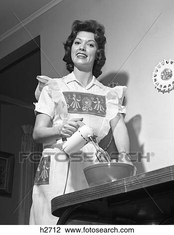 1950S 1960S Smiling Housewife Wearing An Apron Looking At Camera Using An Electric Hand Mixer View Large Photo Image Stock Image - 1950S 1960S Smiling Housewife Wearing An Apron Looking At Camera Using An Electric Hand Mixer . Fotosearch