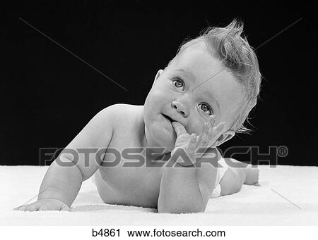 1950s BABY SUCKING THUMB LYING ON BELLY View Large Photo Image Stock Image - 1950s BABY SUCKING THUMB LYING ON BELLY. Fotosearch