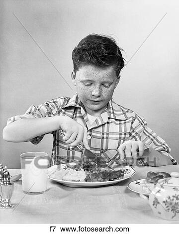 1950S Boy Eating Dinner Cutting Meat With Knife Glass Of Milk View Large Photo Image Stock Photo - 1950S Boy Eating Dinner Cutting Meat With Knife Glass Of Milk. Fotosearch