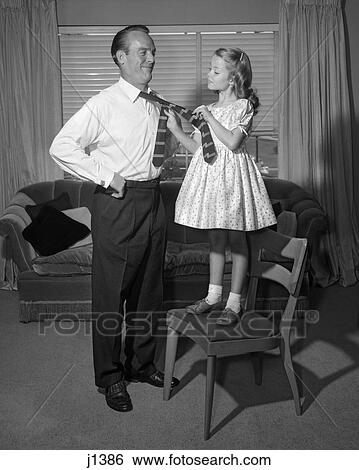 1950S Confident Little Girl Standing On Chair Tying Necktie For Her Smiling Father View Large Photo Image Stock Photograph - 1950S Confident Little Girl Standing On Chair Tying Necktie For Her Smiling Father. Fotosearch
