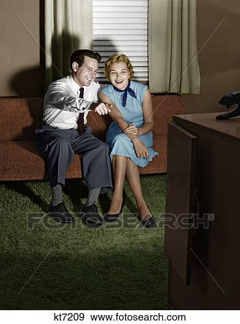 1950S Couple In Darkened Living Room Watching Tv With Husband Pointing At Screen View Large Photo Image Stock Photo - 1950S Couple In Darkened Living Room Watching Tv With Husband Pointing At Screen. Fotosearch