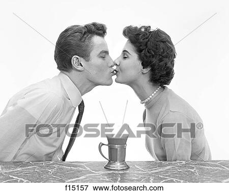 Stock Photo - 1950S Couple Man Woman Kissing Profile Romance Date At Marble Counter One Drink Malt Shake With Two Straws Share Teens Teenagers. Fotosearch
