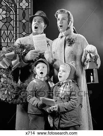1950s FAMILY OF FOUR SON DAUGHTER SINGING CHRISTMAS CAROLS DAD HOLDING WREATH MOM HOLDING CANDLE LANTERN View Large Photo Image Picture - 1950s FAMILY OF FOUR SON DAUGHTER SINGING CHRISTMAS CAROLS DAD HOLDING WREATH MOM HOLDING CANDLE LANTERN. Fotosearch