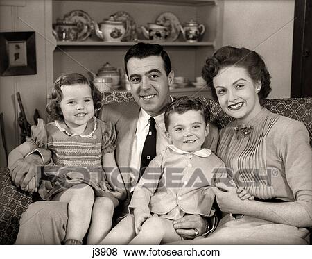 Stock Photo - 1950s FAMILY SITTING ON LIVING ROOM COUCH TOGETHER SMILING LOOKING AT CAMERA. Fotosearch