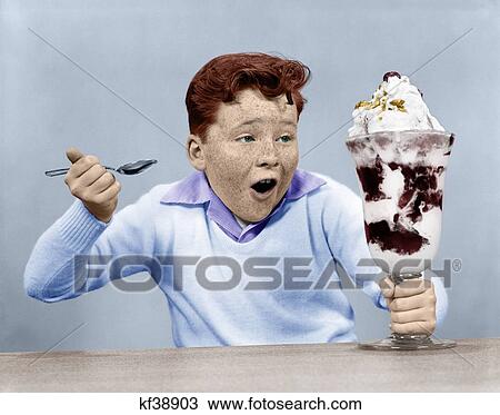 Stock Image - 1950S Freckle Face Boy Digging Into Giant Ice Cream Sundae. Fotosearch