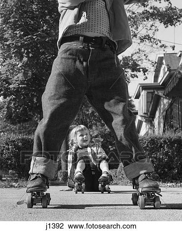 1950S Girl Fallen Sitting Sidewalk Wear Metal Roller Skates Shot Through Legs Of Boy Rolled Cuff Blue Jeans View Large Photo Image Stock Image - 1950S Girl Fallen Sitting Sidewalk Wear Metal Roller Skates Shot Through Legs Of Boy Rolled Cuff Blue Jeans . Fotosearch