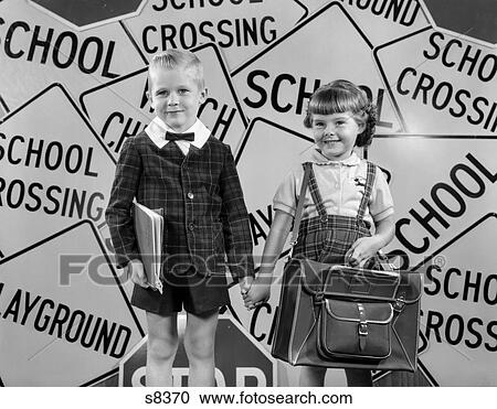 Stock Image - 1950s MONTAGE OF BOY & GIRL IN PLAID JACKET & SKIRT HOLDING HANDS LOOKING AT CAMERA SUPERIMPOSED OVER SCHOOL CROSSING SIGNS. Fotosearch