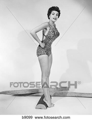 1950S Pin-Up Portrait Of Smiling Woman Wearing Leopard Skin Print Bathing Suit Posing With Hands On Hips Standing On Log View Large Photo Image Stock Photo - 1950S Pin-Up Portrait Of Smiling Woman Wearing Leopard Skin Print Bathing Suit Posing With Hands On Hips Standing On Log. Fotosearch